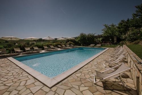 a swimming pool with chairs and umbrellas in a yard at Agriturismo Bricco San Giovanni in Isola d'Asti