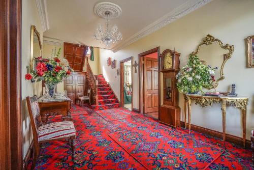 a hallway with a red carpet and a stairway at Tattykeel House in Omagh