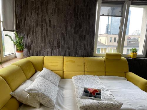 a yellow couch in a room with windows at Grey Gucci Apartment City Center in Warsaw