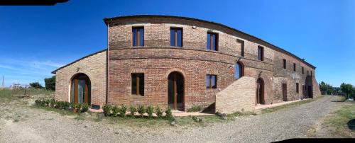 un grand bâtiment en briques avec des fenêtres bleues. dans l'établissement Podere Fogliano, à Sienne