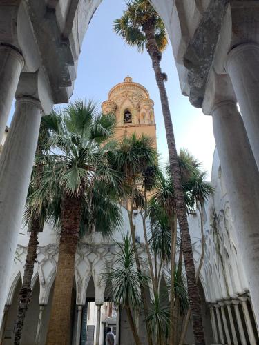 a building with palm trees and a clock tower at Strit strit centro storico in Amalfi