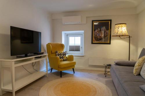 a living room with a television and a yellow chair at Modern Apartment in the City Center of Bad Ischl in Bad Ischl
