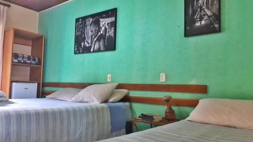 a bedroom with two beds and a green wall at Pousada Recanto da Chapada in Mucugê