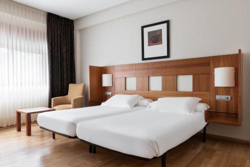 a bedroom with a large white bed and a chair at Exe Vía Argentum in Silleda