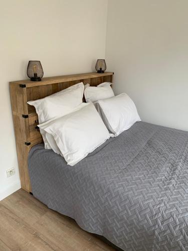 1 cama con cabecero de madera y almohadas blancas en Beautiful studio located south of Paris, en Bourg-la-Reine