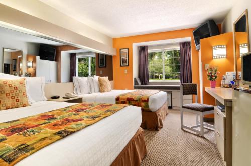 a hotel room with two beds and a desk at Hometown Inn & Suites Jacksonville Butler Blvd./Southpoint in Jacksonville