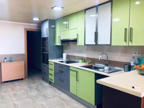 una cocina con armarios verdes y fregadero en Piso lujoso, en Puerto de Mazarrón
