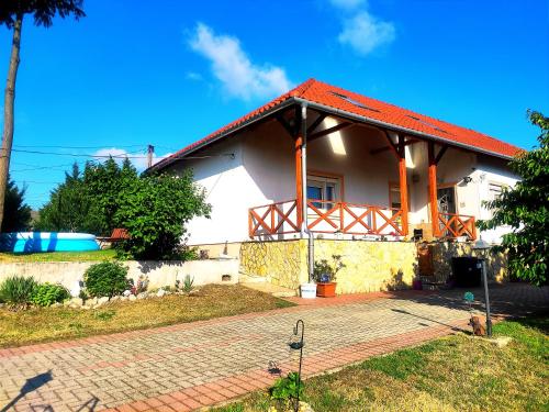 a white house with a red roof at Szandra Vendégház in Öskü