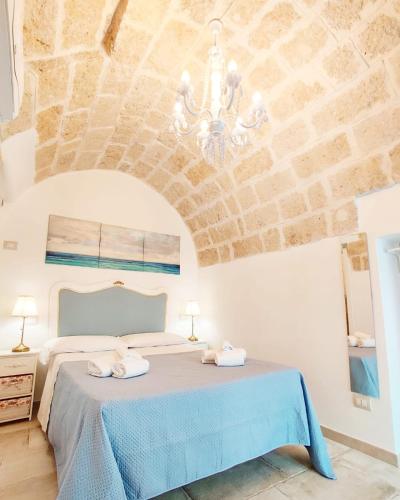 a bedroom with a blue bed and a stone wall at RomAntica in Polignano a Mare