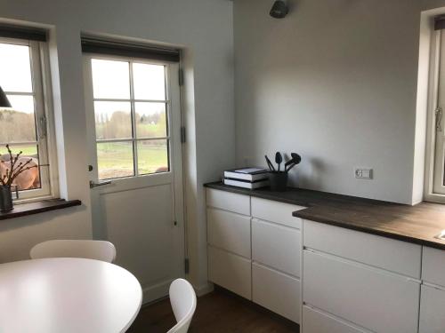 a kitchen with white cabinets and a table and a window at Poolhouse, no smoking everywhere in Kvistgård