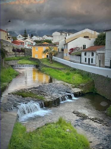 a river with a waterfall in a small town at Casa na Ribeira in Ribeira Grande