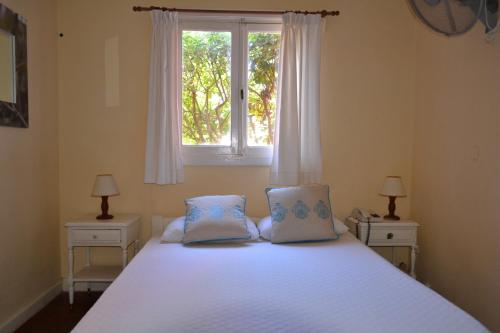 1 dormitorio con 1 cama blanca grande y 2 mesitas de noche en Hosteria Belvedere en Pinamar