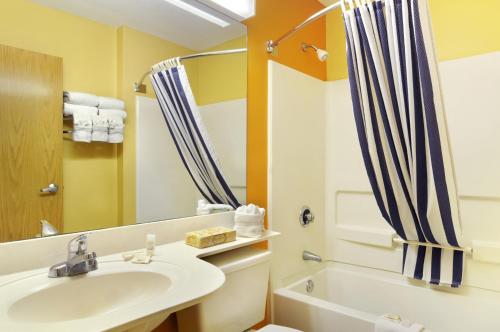 a bathroom with a sink and a shower curtain at Hometown Inn & Suites Jacksonville Butler Blvd./Southpoint in Jacksonville