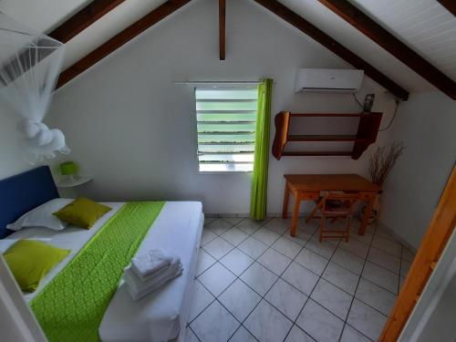 Un dormitorio con una cama y una mesa y una ventana. en Villa MANGO, en Deshaies