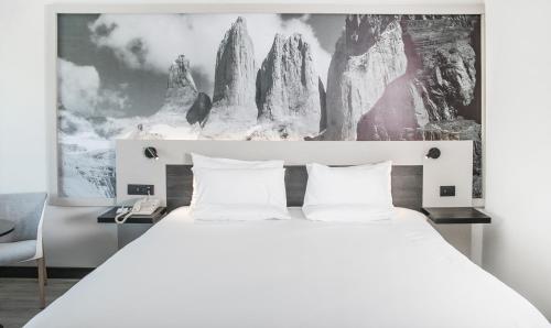 a bedroom with a large white bed with a picture on the wall at Novotel Santiago Vitacura in Santiago