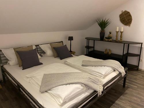 uma cama com lençóis brancos e almofadas num quarto em Im Herzen Bayerns em Töging am Inn