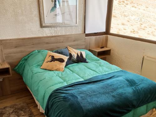 um quarto com uma cama verde com duas almofadas em El Colorado Ski depto In Out 2 ambientes em Farellones