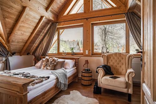 a bedroom with a bed and a chair and a window at Nosalowski Wypas in Zakopane