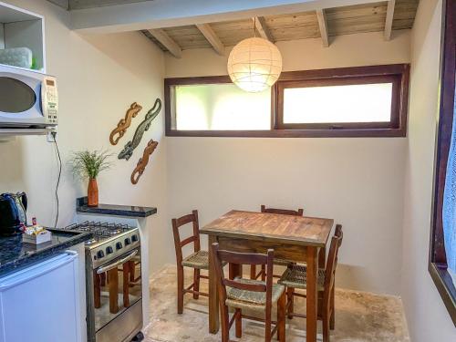 a kitchen with a table with chairs and a microwave at Morada da Praia do Rosa Pousada in Praia do Rosa