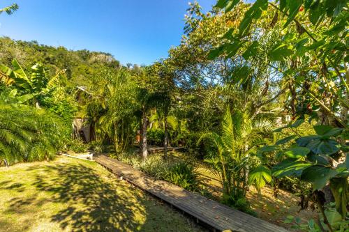 a wooden path through a lush green forest with trees at Morada da Praia do Rosa Pousada in Praia do Rosa