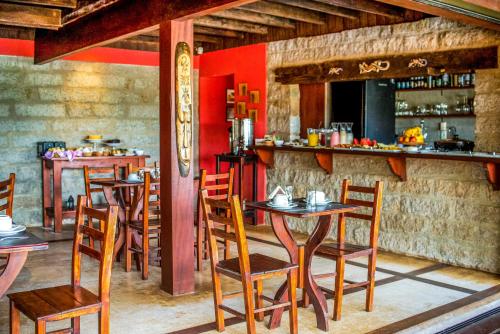 un restaurante con mesas de madera y sillas en una habitación en Morada da Praia do Rosa Pousada, en Praia do Rosa