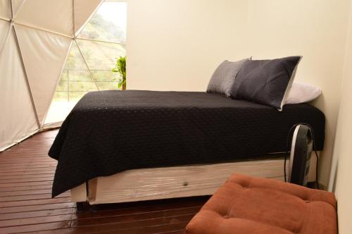 a bedroom with a bed with a black blanket and a window at La Quinta Dimensión Glamping Resort in El Peñol