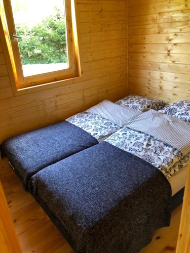 a bed in a wooden cabin with a window at Chatka Uchatka in Stronie Śląskie