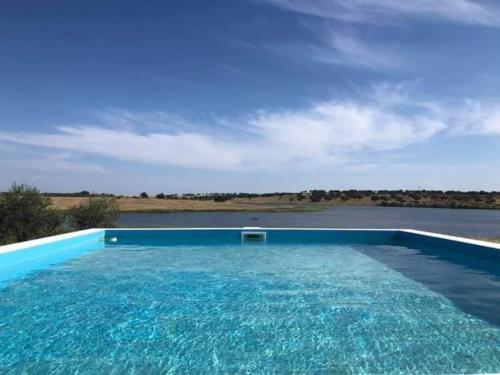 uma grande piscina azul ao lado de um corpo de água em Monte da Figueira em Amareleja