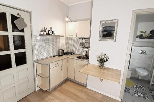 una piccola cucina con armadi bianchi e lavandino di Weneda a Dębki