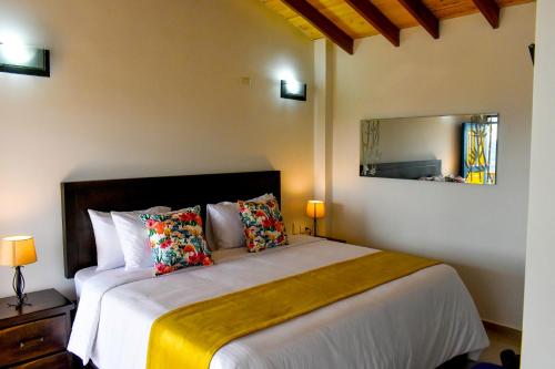 1 dormitorio con 1 cama grande y espejo en Ecohotel Guaduales Pereira en Pereira