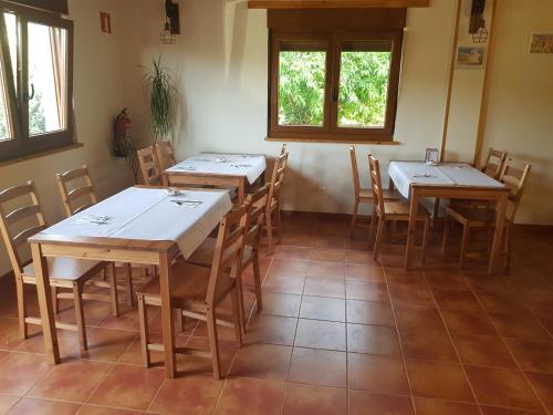 uma sala de jantar com mesas, cadeiras e janelas em La Oliva em Oreña