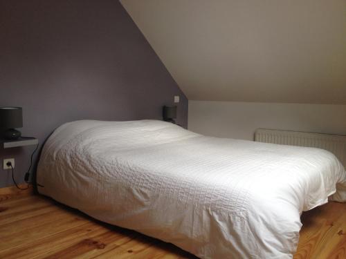 OG Gîte في Le Minihic-sur-Rance: سرير أبيض كبير في غرفة مع أرضية خشبية