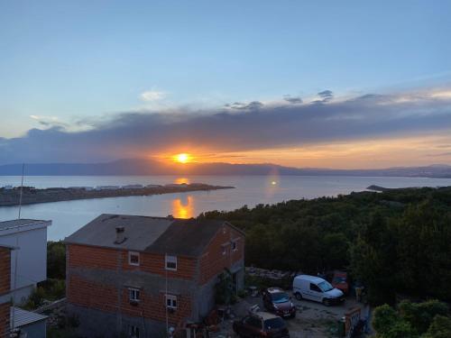 a sunset over a body of water with a building at Apartments Michael & Petra , Omisalj, Insel Krk, Kroatien in Omišalj