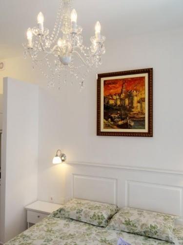 a white bedroom with a chandelier and a bed at Apartments Jasmina in Korčula