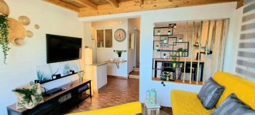 a living room with a yellow couch and a television at ARGUINEGUIN, two bedrooms bungalow, pool & wifi in Arguineguín