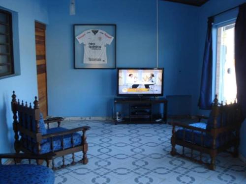 un salon avec des murs bleus et une télévision dans l'établissement Pousada do Ze Louquinho, à Aparecida