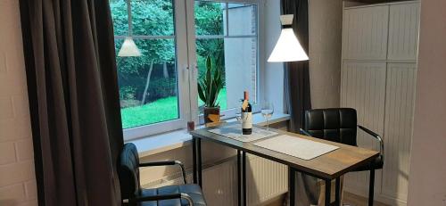 Zimmer mit einem Tisch mit einer Flasche Wein und einem Fenster in der Unterkunft Ferienwohnung am Treene-Ufer bei Flensburg in Oeversee