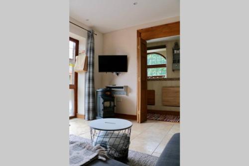 a living room with a table and a television at Cwtch Bach - Garnant in Ammanford