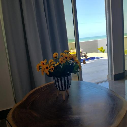 a vase filled with yellow flowers sitting on a table at Vilamar in Tibau do Sul