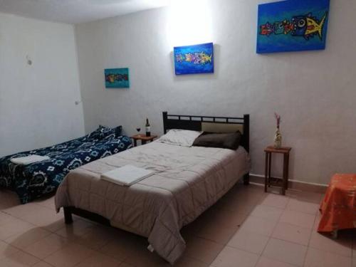 a bedroom with two beds and paintings on the wall at Private Room in Cozumel