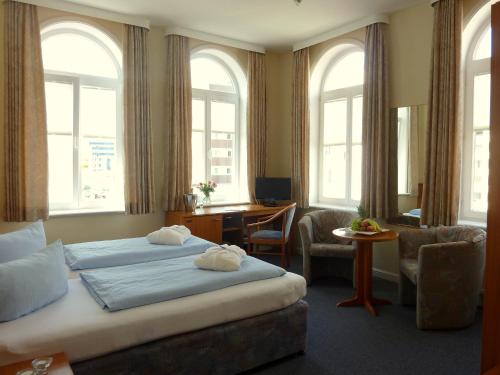 ヴェスターラントにあるMarin Hotel Syltのベッド2台とデスクが備わるホテルルームです。