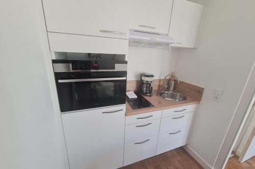 a small kitchen with white cabinets and a sink at Le Poulorio 9 - Studio - Proche Gare By Locly in Lorient