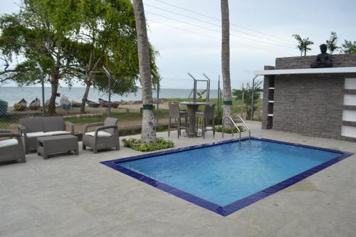 a swimming pool with chairs and a table and the ocean at Condominio Atlantis in Coveñas