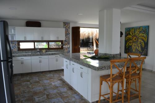 a kitchen with white cabinets and a counter with two chairs at Condominio Atlantis in Coveñas