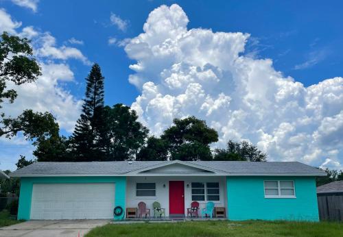 a house with a red door and chairs at Curly Sunshine Clearwater in Clearwater