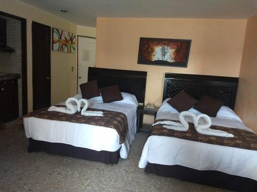 a hotel room with two beds with white towels on them at Suite en torres gemelas con vista al mar in Acapulco