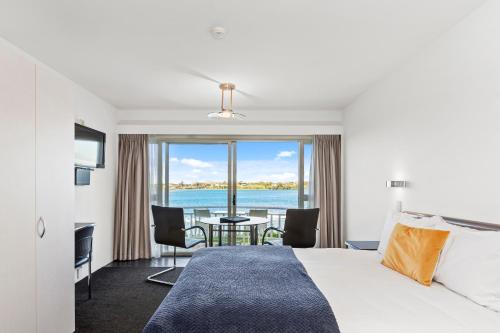 a hotel room with a bed and a view of the ocean at The Tauranga on the Waterfront in Tauranga