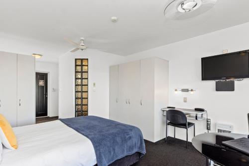 a bedroom with a bed and a desk and a tv at The Tauranga on the Waterfront in Tauranga