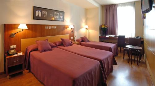 a hotel room with two beds and a table at Bahia de Chapela in Redondela