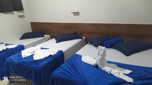 3 camas en una habitación con sábanas azules y almohadas azules en Pousada Quarto com frigobar,ar e garagem gratuita, en Aparecida